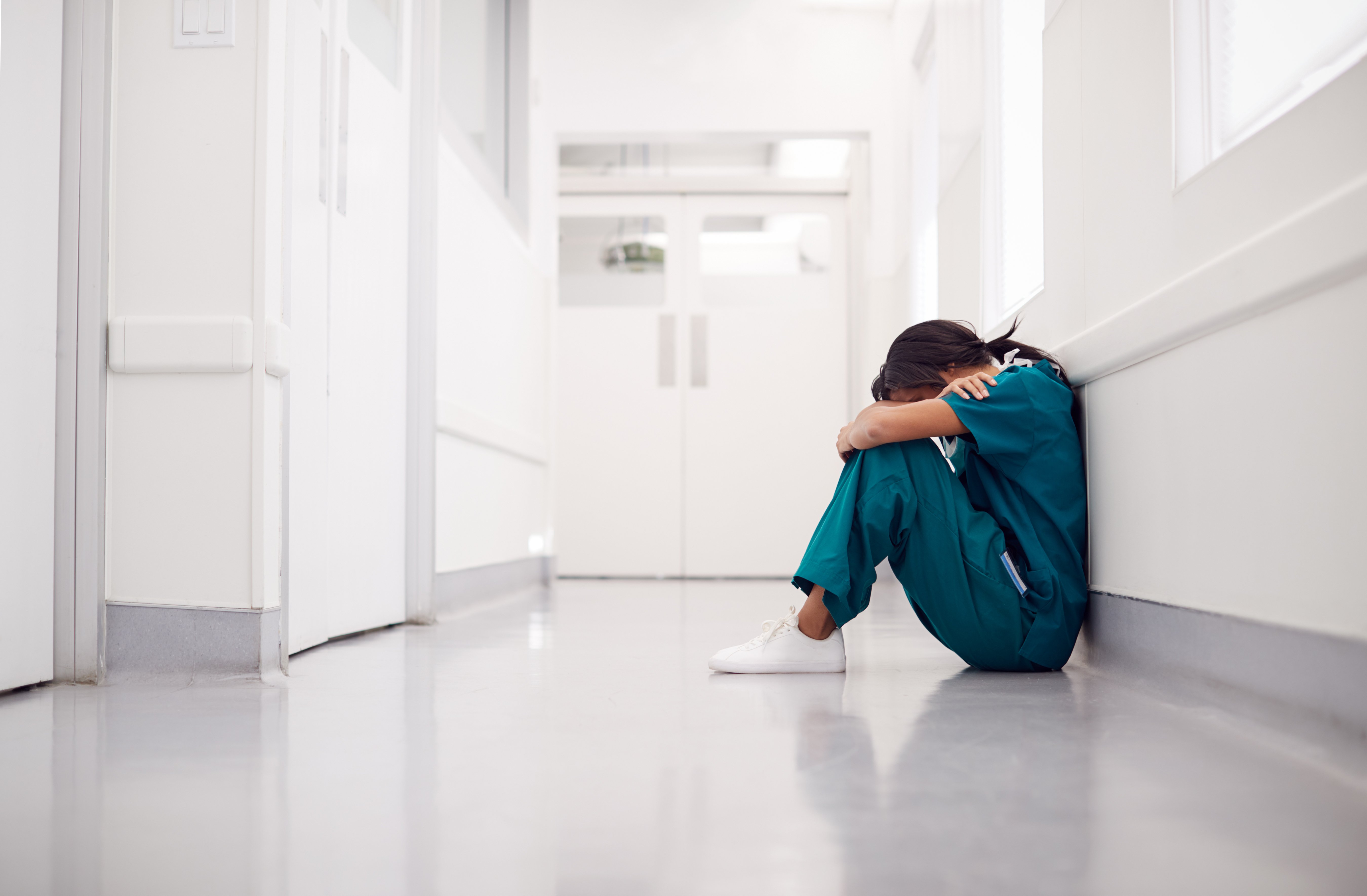 Eine Medizinerin sitzt alleine in einem Krankenhausgang