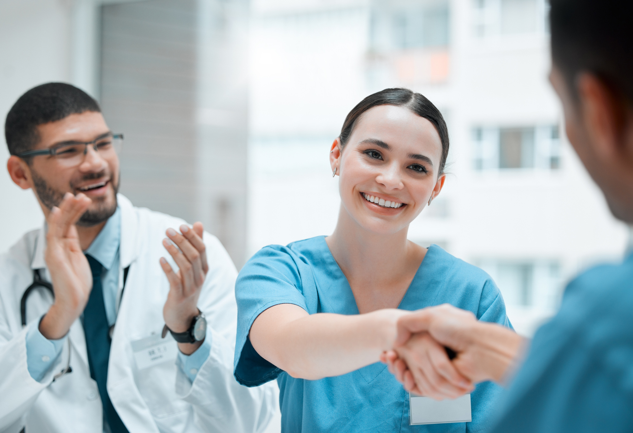 Eine junge medizinische Fachangestellte schüttelt die Hand eines Arztes, während andere um sie herum applaudieren – Titelbild jameda Blogpost
