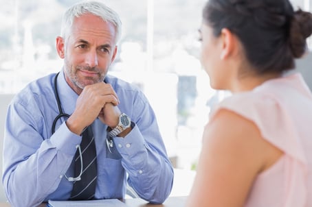 Serious doctor listening to patient explaining her painful in his office